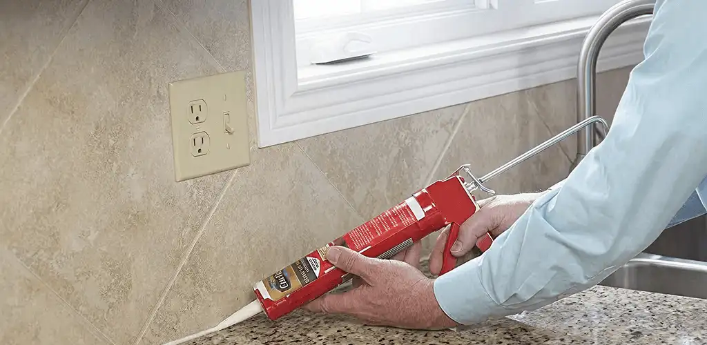 Handyman applying caulk along a kitchen backsplash and countertop seam in Knoxville, TN