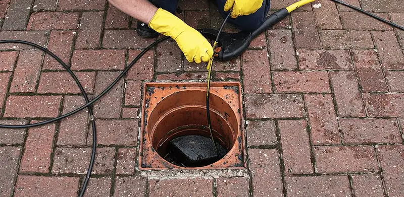 Drain cleaning technician using a drain snake to clear a clogged drain in Knoxville, TN