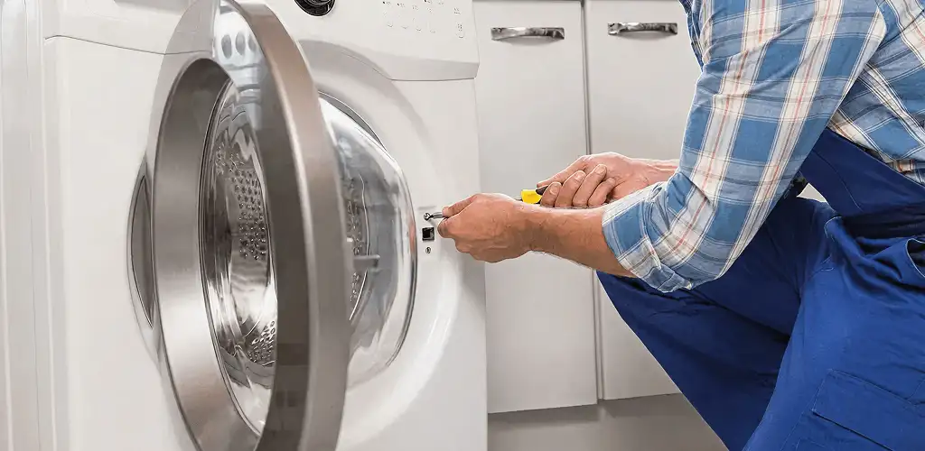 Handyman repairing a clothes dryer and checking electrical connections in Knoxville, TN