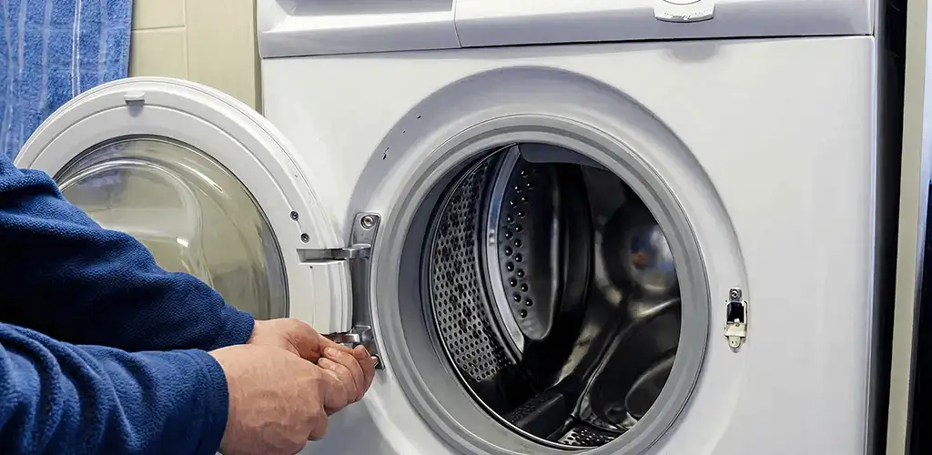 Washing machine repair handyman checking a front-load washer door and latch in Knoxville, TN