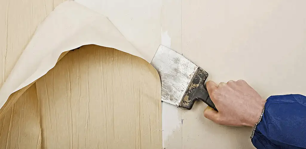 Handyman removing wallpaper with a scraper for wall preparation in Knoxville, TN