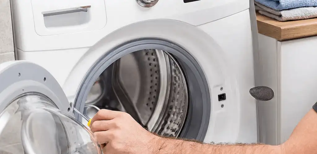 Handyman repairing a front-load washing machine and inspecting the drum in Knoxville, TN