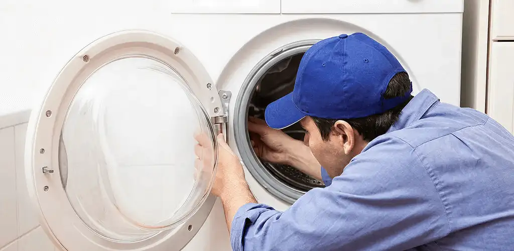 Washing machine repair handyman inspecting a front-load washer drum in Knoxville, TN
