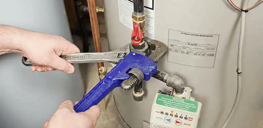 Water heater repair technician tightening the shutoff valve and supply line in Knoxville, TN